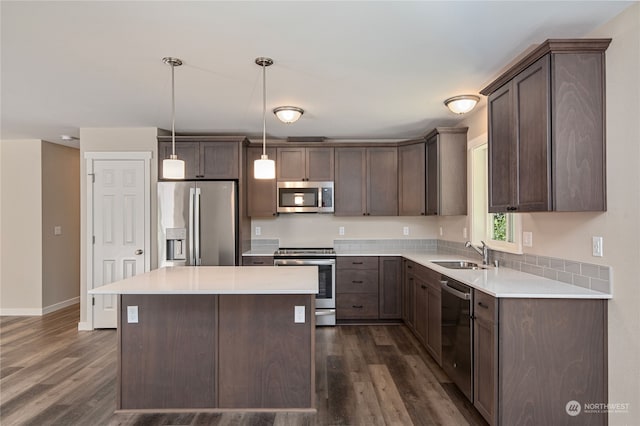 kitchen with sink, dark wood-type flooring, a kitchen island, and stainless steel appliances