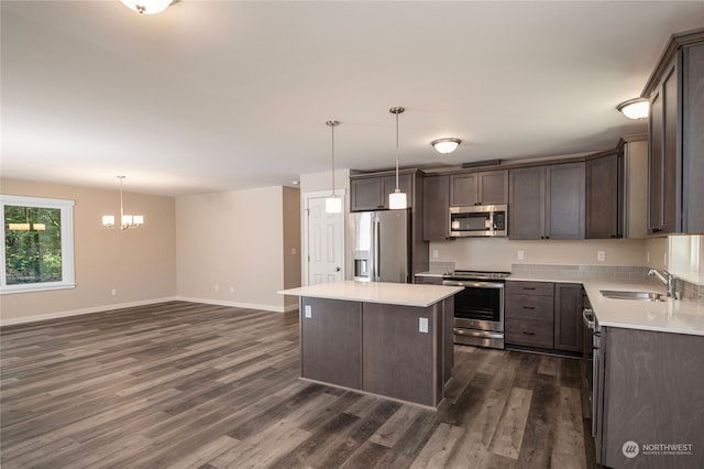 kitchen with dark hardwood / wood-style floors, stainless steel appliances, decorative light fixtures, a center island, and sink