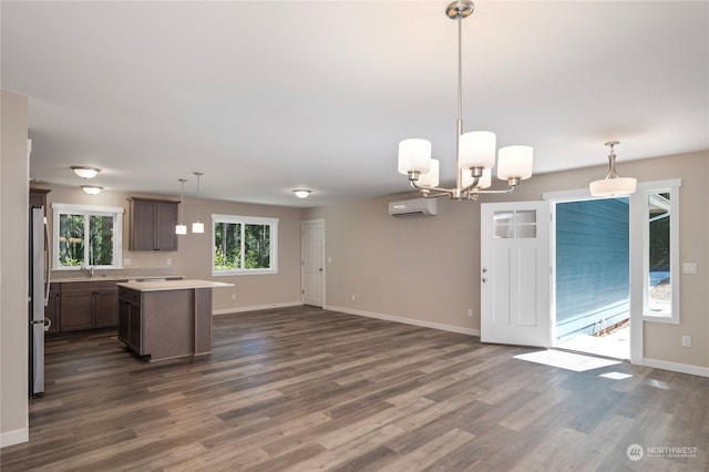 kitchen with hardwood / wood-style flooring, stainless steel refrigerator, a kitchen island, and pendant lighting