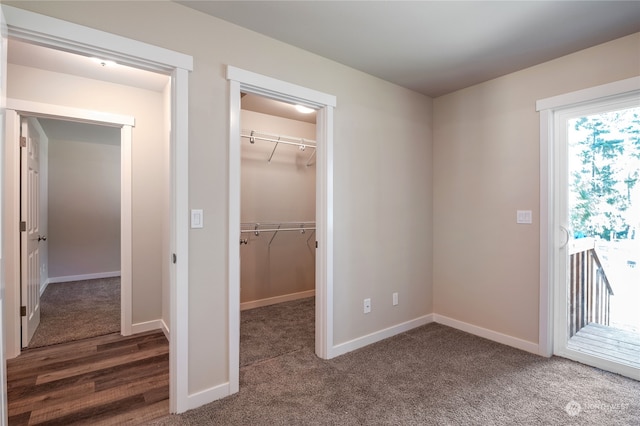 unfurnished bedroom featuring dark colored carpet, a spacious closet, and a closet