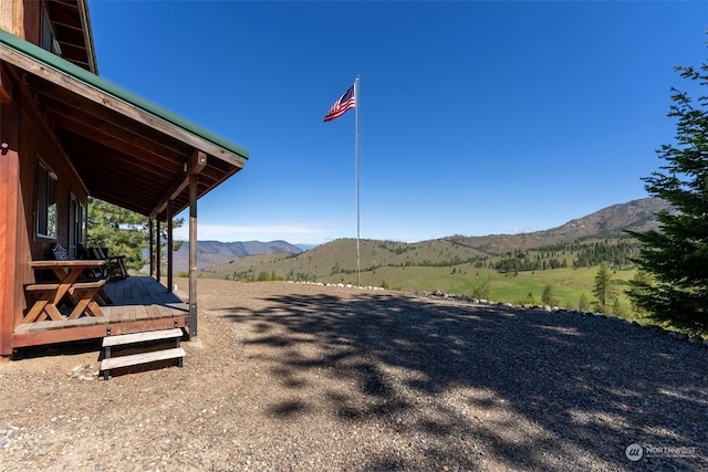 view of yard with a deck with mountain view and a rural view