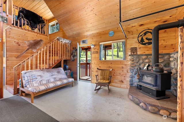 bedroom with concrete floors, wood walls, a wood stove, high vaulted ceiling, and wood ceiling