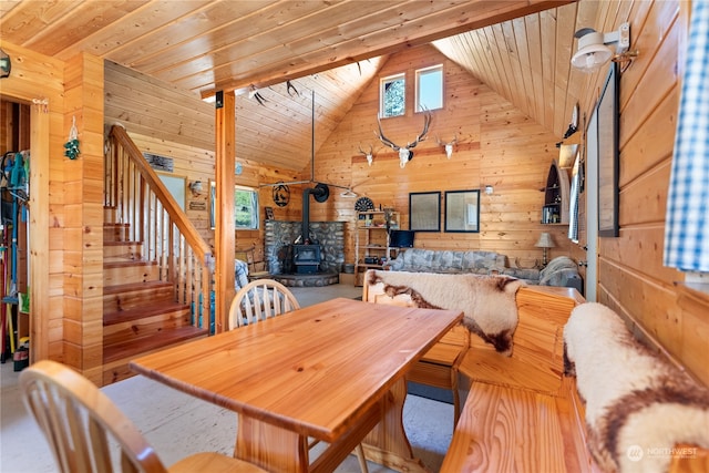 dining space featuring high vaulted ceiling, wood walls, a wood stove, and wood ceiling