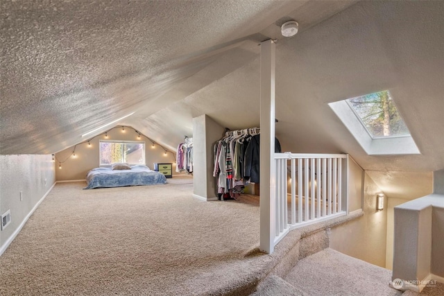 bedroom with lofted ceiling with skylight, carpet, and a textured ceiling