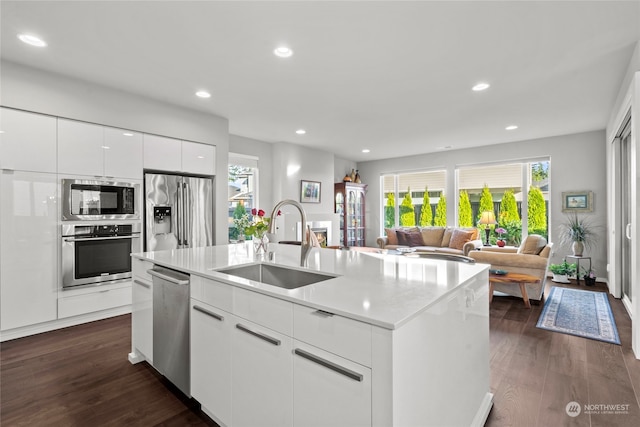 kitchen with dark wood-type flooring, white cabinets, sink, an island with sink, and appliances with stainless steel finishes