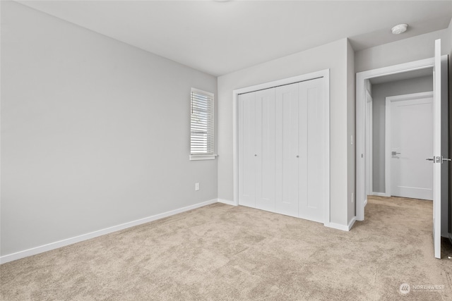 unfurnished bedroom with a closet and light colored carpet