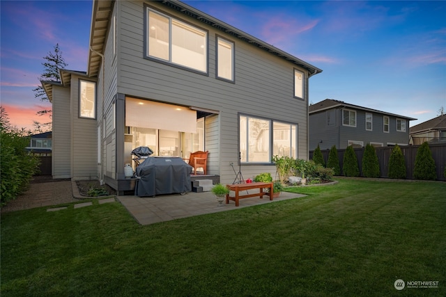 back house at dusk with a yard and a patio