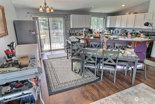 dining space with a notable chandelier, plenty of natural light, dark hardwood / wood-style flooring, and lofted ceiling