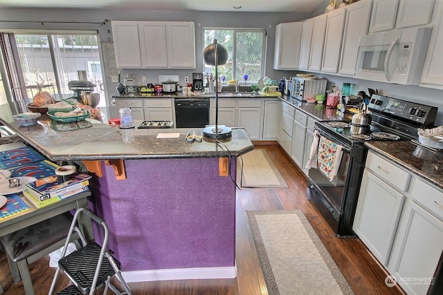 kitchen featuring white cabinetry, plenty of natural light, black appliances, and dark hardwood / wood-style floors