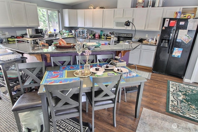 kitchen with white cabinets, a kitchen breakfast bar, dark hardwood / wood-style flooring, and black appliances