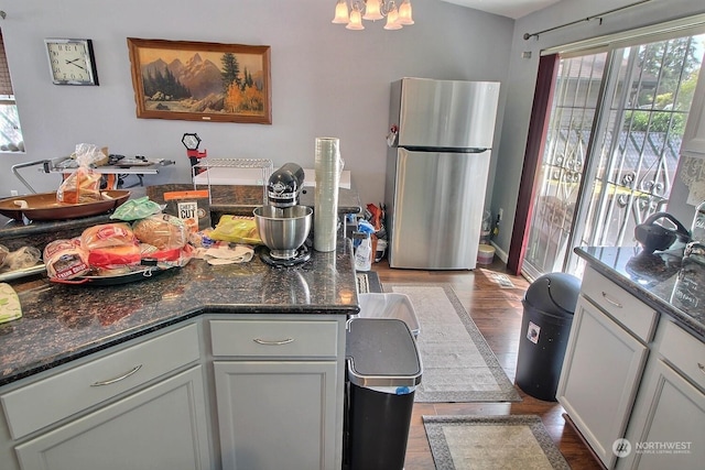 kitchen featuring stainless steel fridge, dark hardwood / wood-style flooring, and dark stone counters