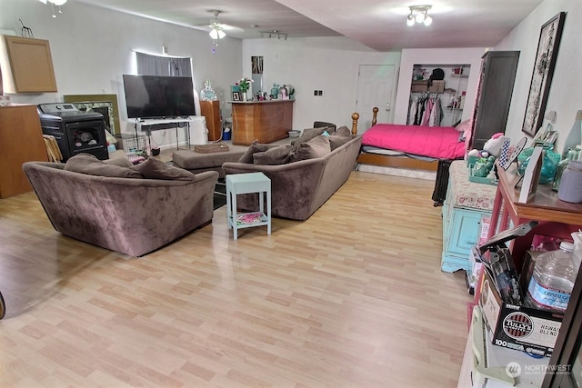 living room featuring light wood-type flooring, a wood stove, and ceiling fan