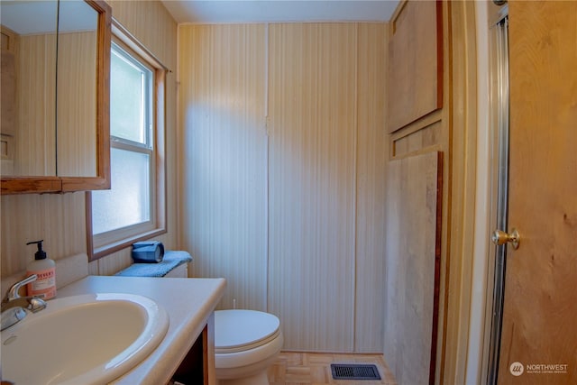 bathroom with vanity, toilet, parquet flooring, and walk in shower