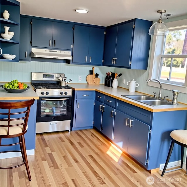 14607 Union Ave SW, Lakewood, WA 98498 - kitchen with under cabinet range hood, stainless steel range with gas stovetop, a sink, and blue cabinets