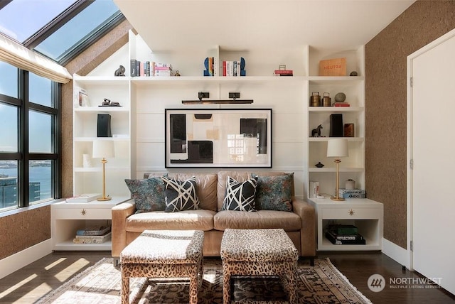 living area with hardwood / wood-style flooring, lofted ceiling with skylight, and a wealth of natural light