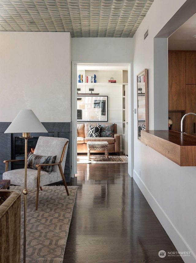 hallway featuring built in shelves, sink, and dark wood-type flooring