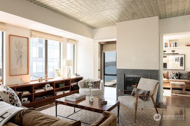 interior space featuring plenty of natural light, a water view, a premium fireplace, and dark wood-type flooring