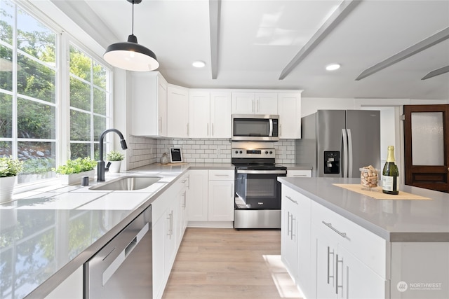 kitchen featuring white cabinetry, sink, pendant lighting, and stainless steel appliances