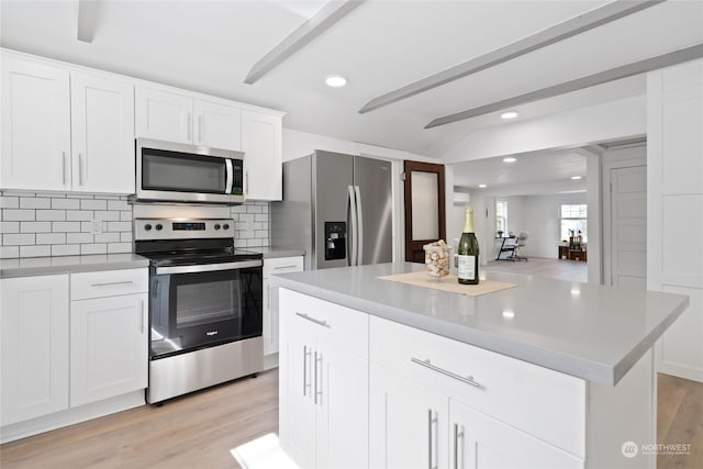 kitchen with decorative backsplash, stainless steel appliances, a kitchen island, and white cabinets