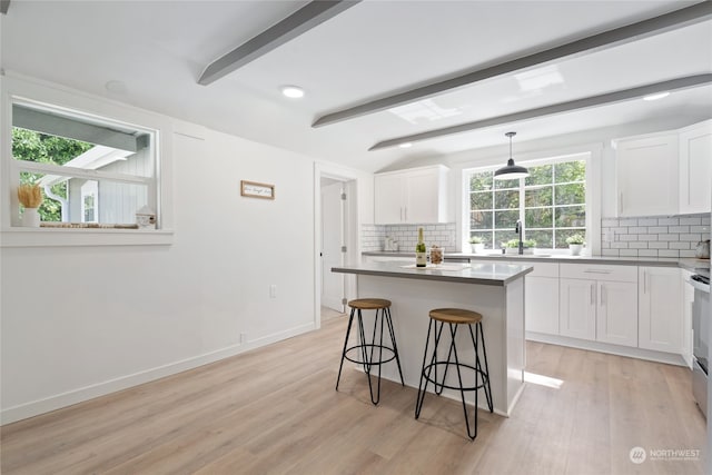 kitchen featuring pendant lighting, a kitchen breakfast bar, a center island, and white cabinets