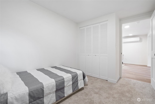 bedroom with a wall mounted AC, light carpet, and a closet