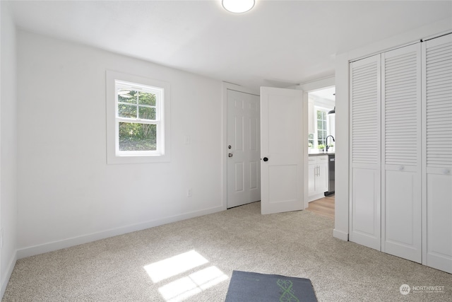 unfurnished bedroom with sink and light colored carpet