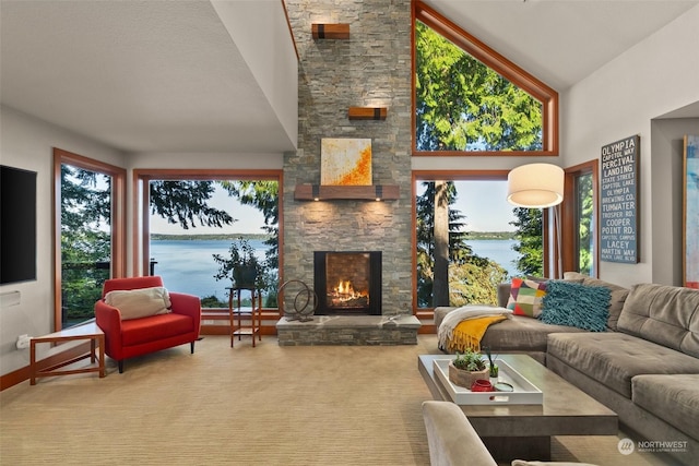 carpeted living room with high vaulted ceiling, a water view, and a stone fireplace