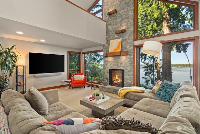 carpeted living room featuring a water view, a fireplace, and high vaulted ceiling