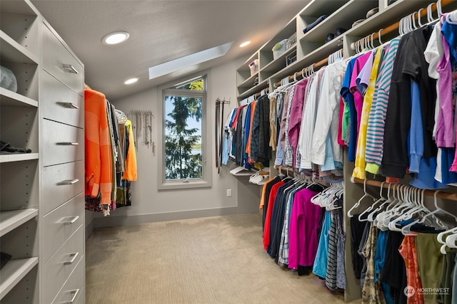 walk in closet with light colored carpet and lofted ceiling