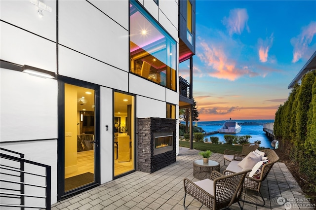 patio terrace at dusk with an outdoor living space and a water view