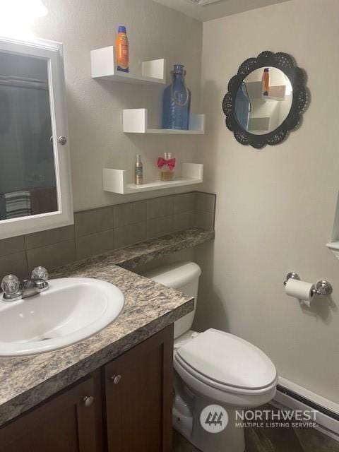 bathroom with vanity, toilet, backsplash, and a baseboard radiator