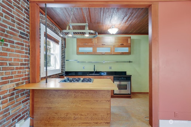 kitchen with appliances with stainless steel finishes, sink, wood ceiling, and brick wall