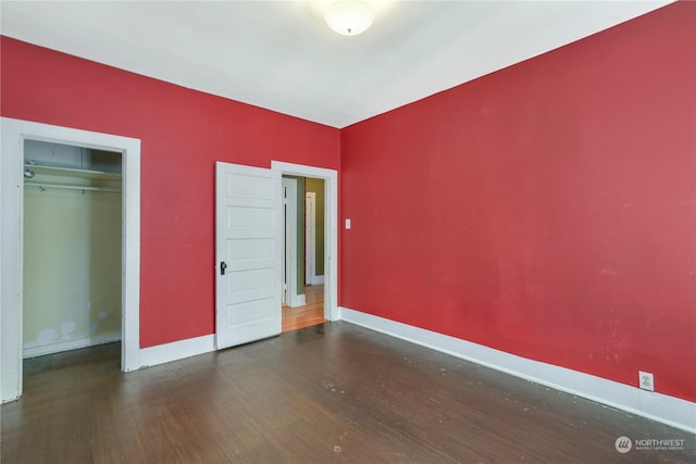 unfurnished bedroom with a closet and dark hardwood / wood-style floors