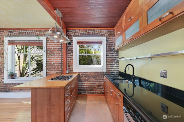 kitchen featuring sink, wooden ceiling, stainless steel gas cooktop, wooden counters, and brick wall