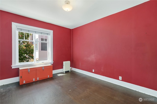 spare room featuring radiator heating unit and dark wood-type flooring