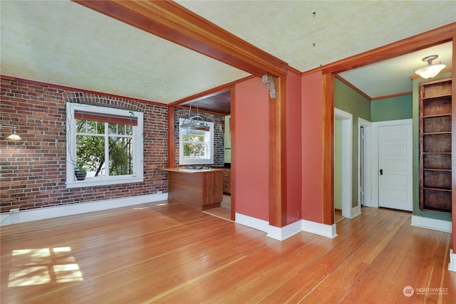 interior space featuring crown molding, brick wall, and light hardwood / wood-style floors