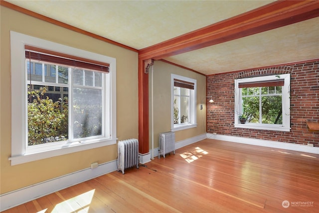 interior space with radiator heating unit, brick wall, and light hardwood / wood-style flooring