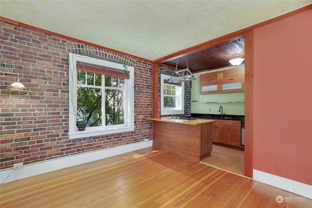 bar featuring pendant lighting, gas stovetop, brick wall, and light hardwood / wood-style flooring