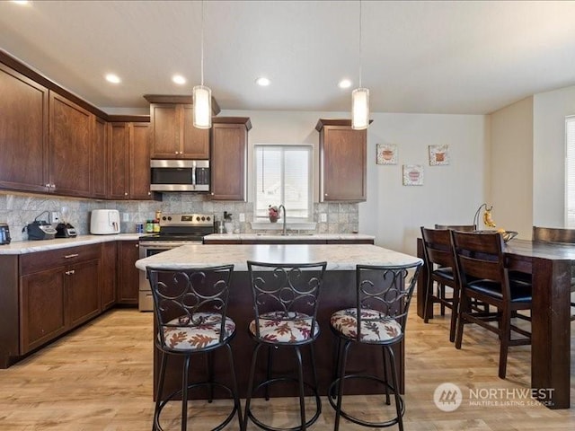 kitchen with stainless steel appliances, a kitchen island, and decorative light fixtures