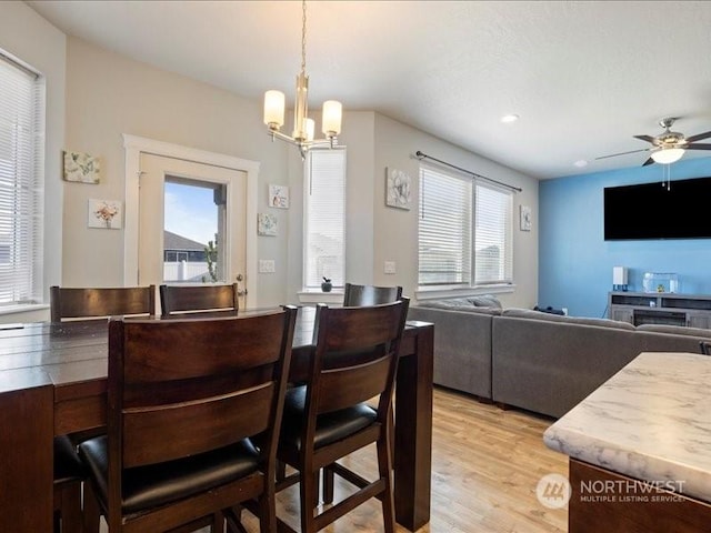 dining room featuring ceiling fan with notable chandelier and light hardwood / wood-style floors