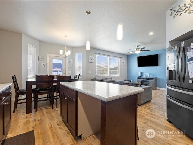 kitchen featuring black refrigerator with ice dispenser, dark brown cabinets, a center island, and pendant lighting