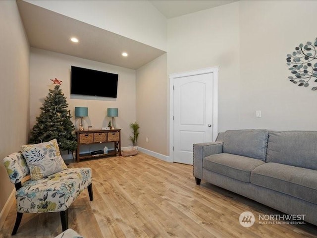 living room featuring light wood-type flooring and a high ceiling