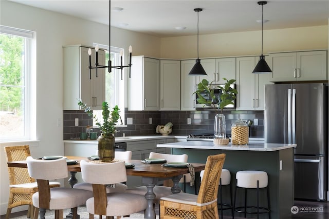 kitchen featuring stainless steel refrigerator, gray cabinetry, a center island, decorative light fixtures, and decorative backsplash