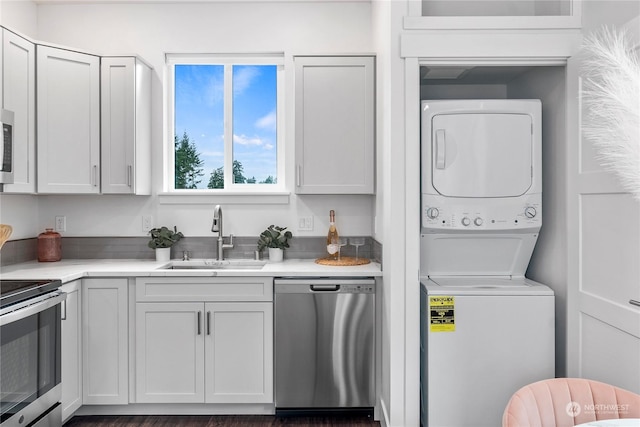 kitchen featuring white cabinetry, stacked washer and dryer, sink, and appliances with stainless steel finishes