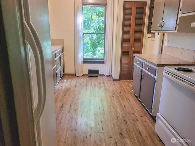 kitchen with light wood-type flooring, white appliances, and gray cabinets