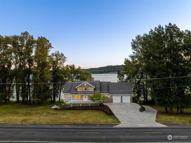 view of front of house featuring a garage, a water view, and a front lawn