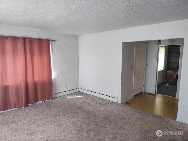 empty room with dark parquet floors, baseboard heating, and a textured ceiling