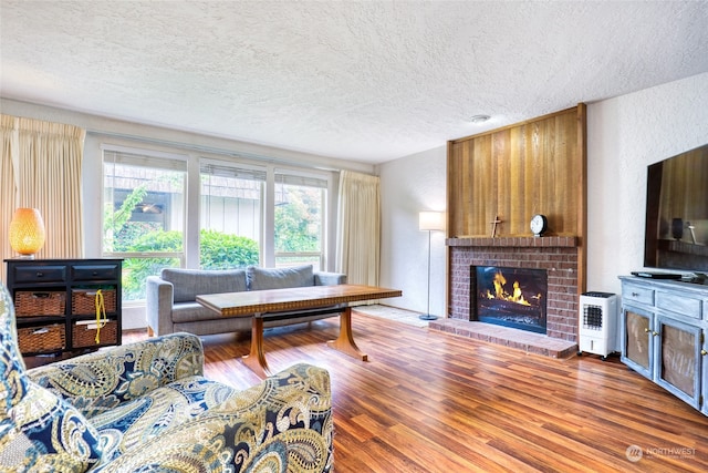 living room featuring a textured ceiling, a fireplace, and wood-type flooring