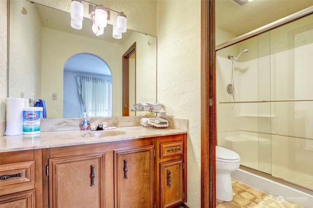 bathroom featuring a shower with door, a textured ceiling, toilet, vanity, and tile patterned floors