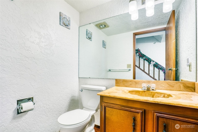 bathroom featuring vanity, a textured ceiling, and toilet